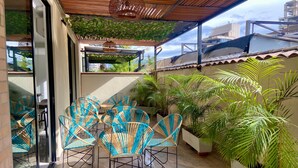 An outdoor patio with wicker chairs and potted plants. - EcoHub Hotel Medellin (Medellín)