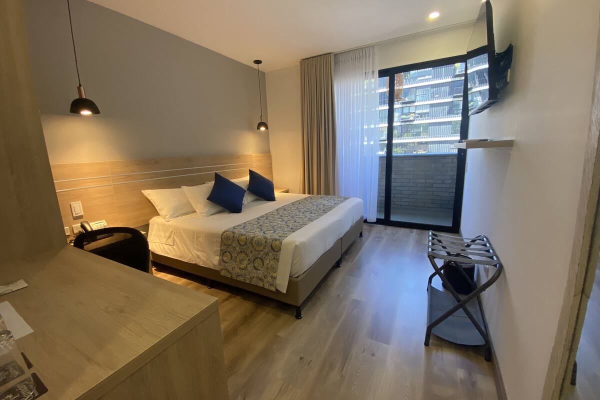 Une chambre d’hôtel avec un lit, une table de chevet, une chaise et une vue sur l’extérieur.