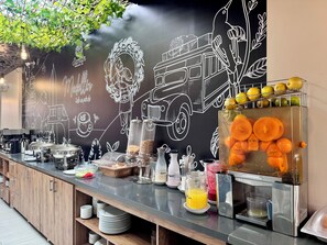 Ein Frühstücksbuffet mit verschiedenen Speisen und einer Tafelwand mit Zeichnungen.