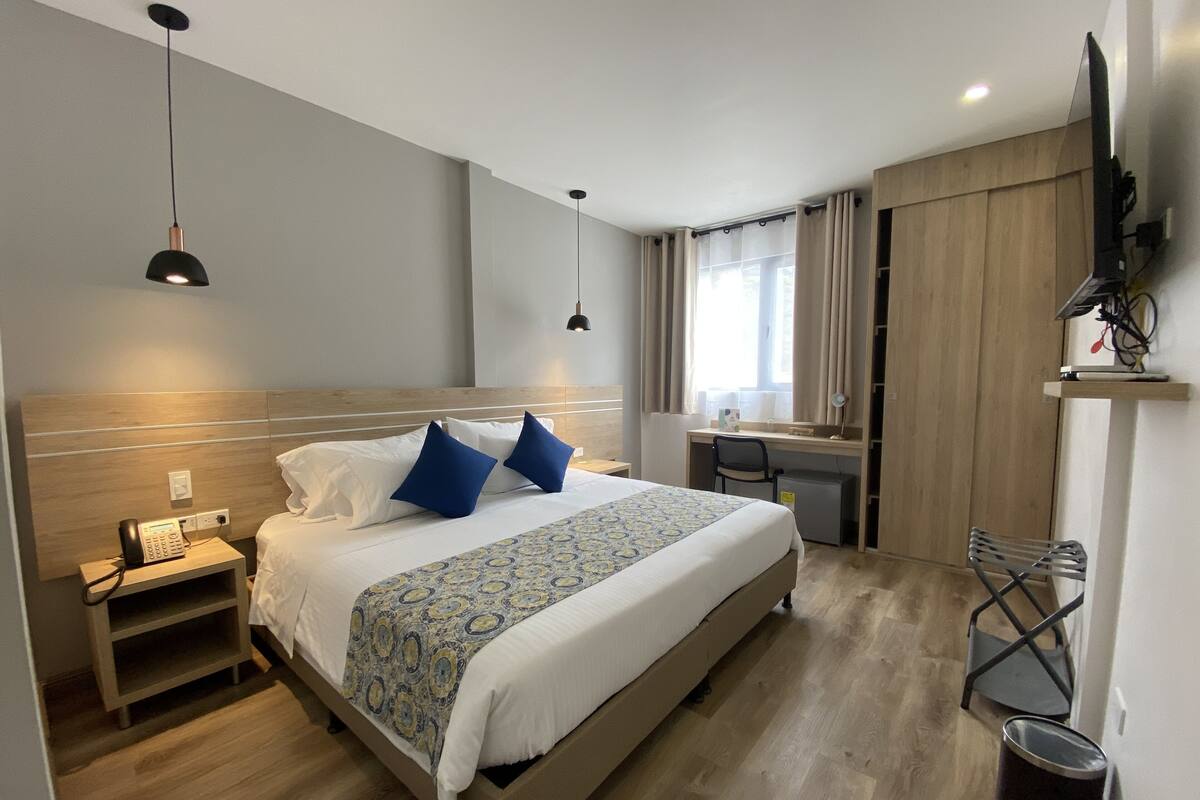 Une chambre d’hôtel comprenant un lit, une table de chevet, un bureau, une chaise et un téléviseur.