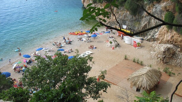 A beach with clear water, umbrellas, and people. - Apartment Sendi - Near the beach, fully equipped (Dubrovnik)