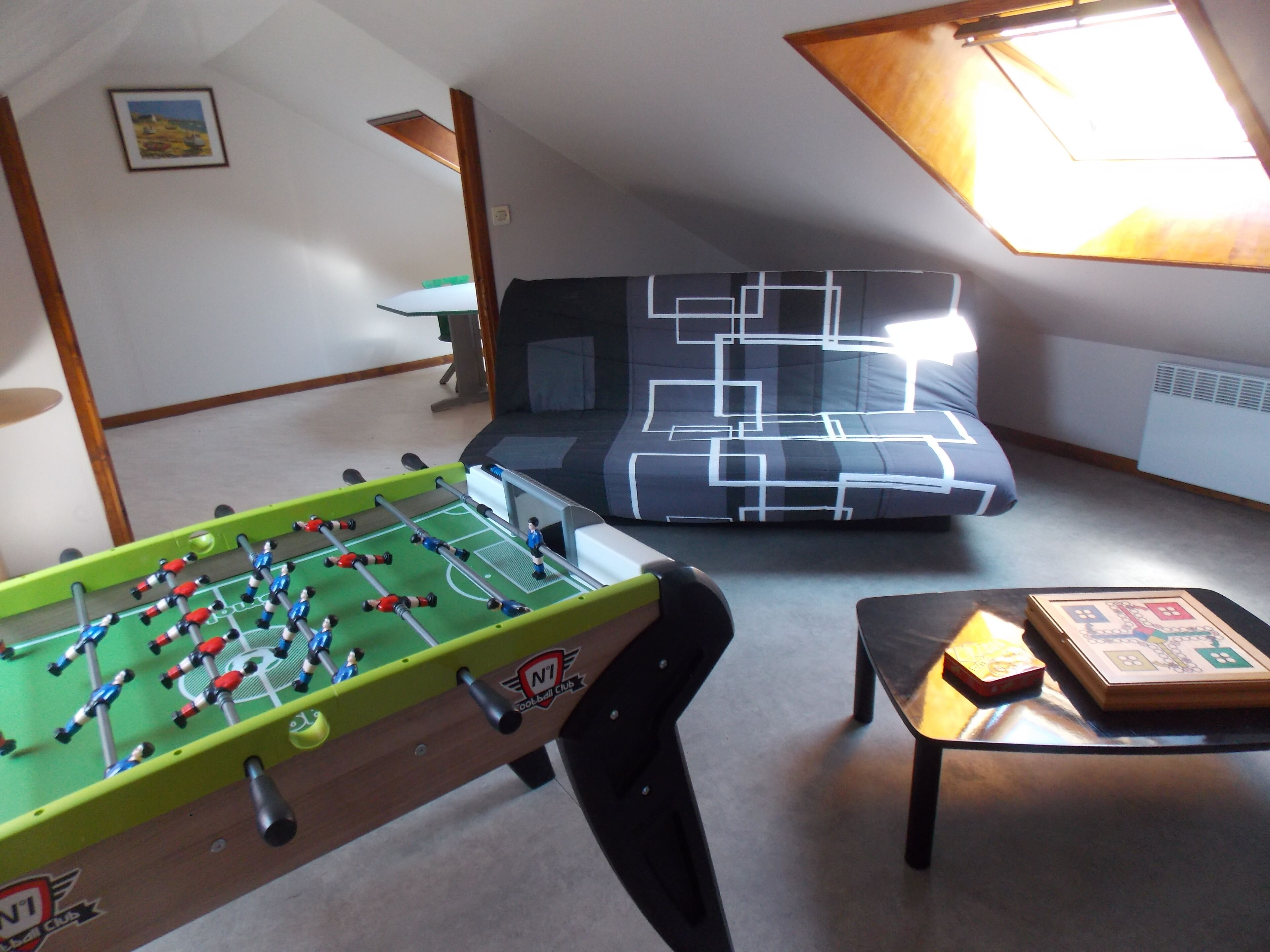 Et værelse med et bordtennisbord, en sofa og et bord med brætspil.