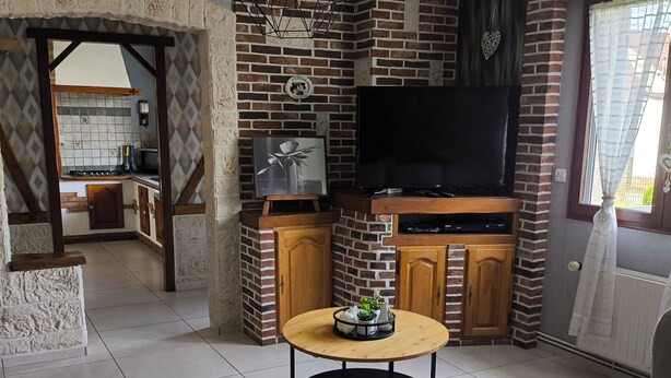 Een moderne woonkamer met een televisie, een ronde houten tafel en een bank.