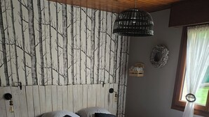 Een slaapkamer met een bed, een houten hoofdbord, wandlampen en een raam met gordijnen.