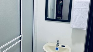 Une petite salle de bain avec un lavabo blanc, un miroir et une serviette accrochée au mur.