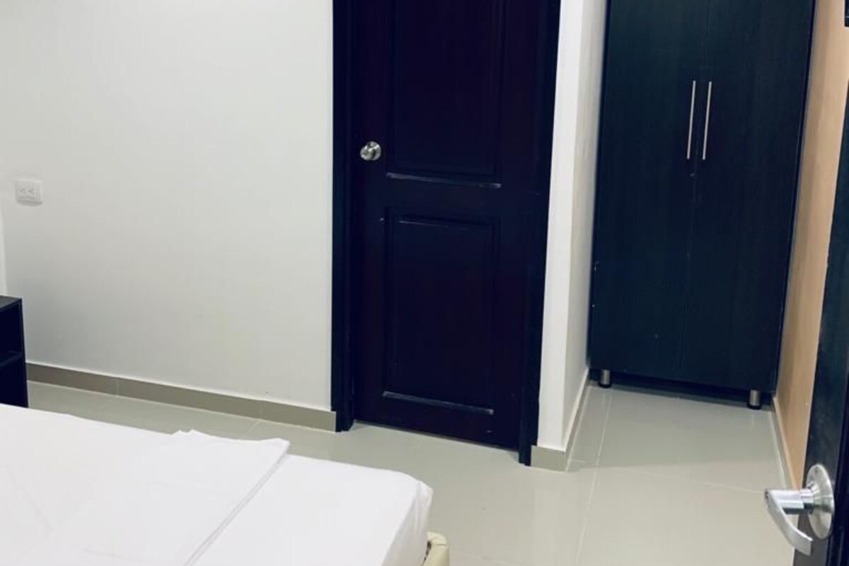 A bedroom with a bed, a wardrobe, and an air conditioning unit.