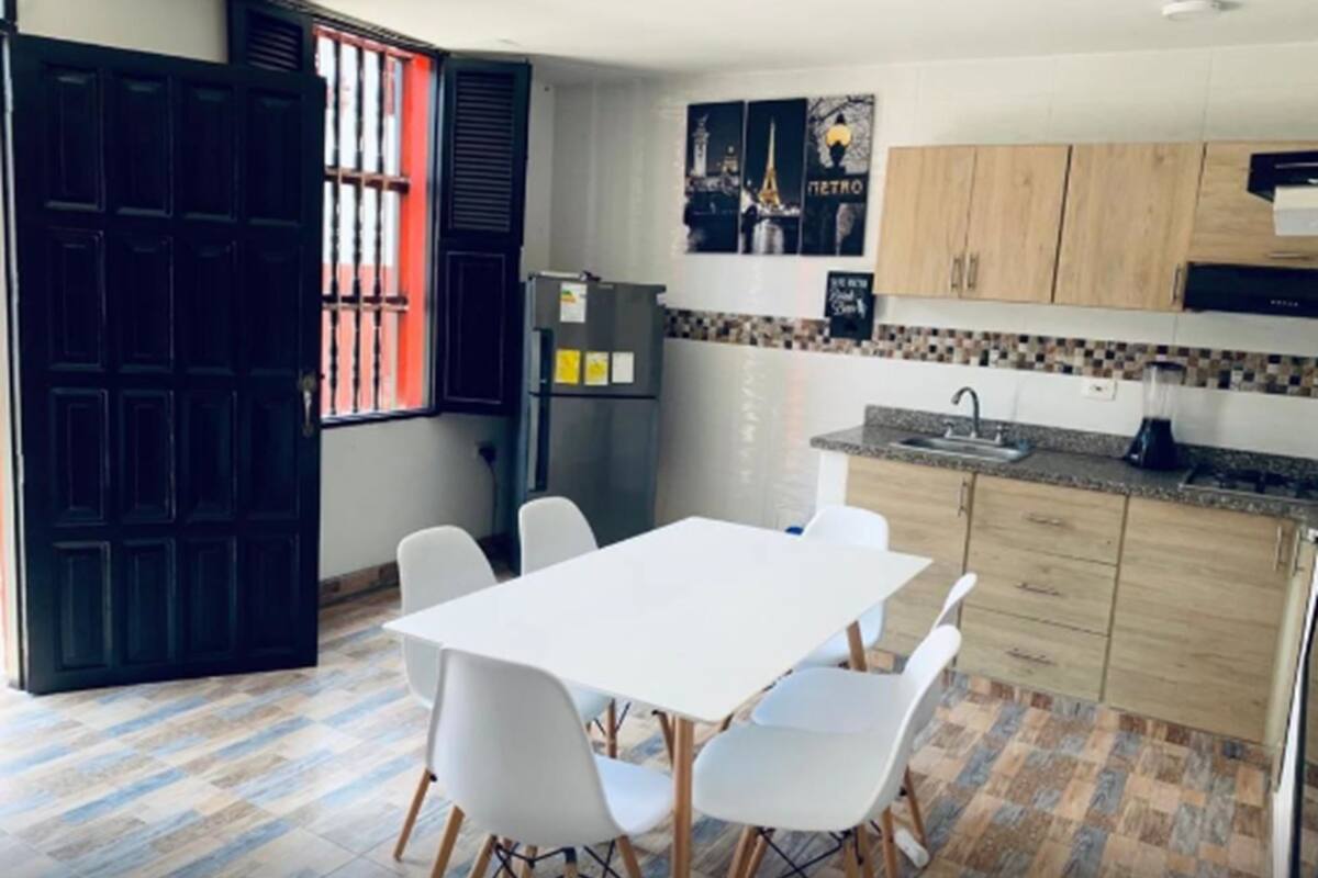 A compact kitchen with a white table and chairs, a refrigerator, and a sink.