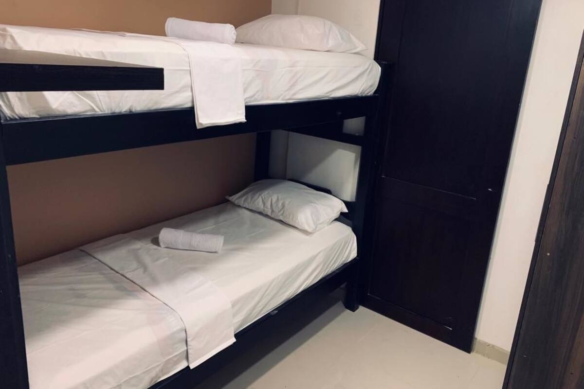 A bunk bed with white bedding and a closed door.
