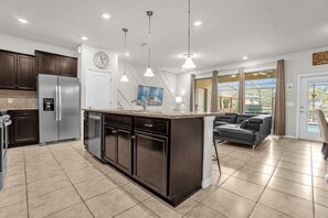Enjoy cooking and relaxing in this well-appointed kitchen and living area with a central island, leather sofa, and flat-screen TV.