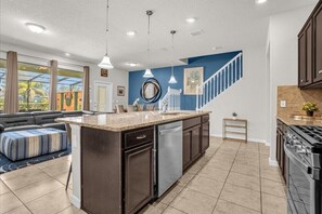 Enjoy cooking in this well-lit kitchen with a large island, dark cabinetry, and stainless steel appliances.
