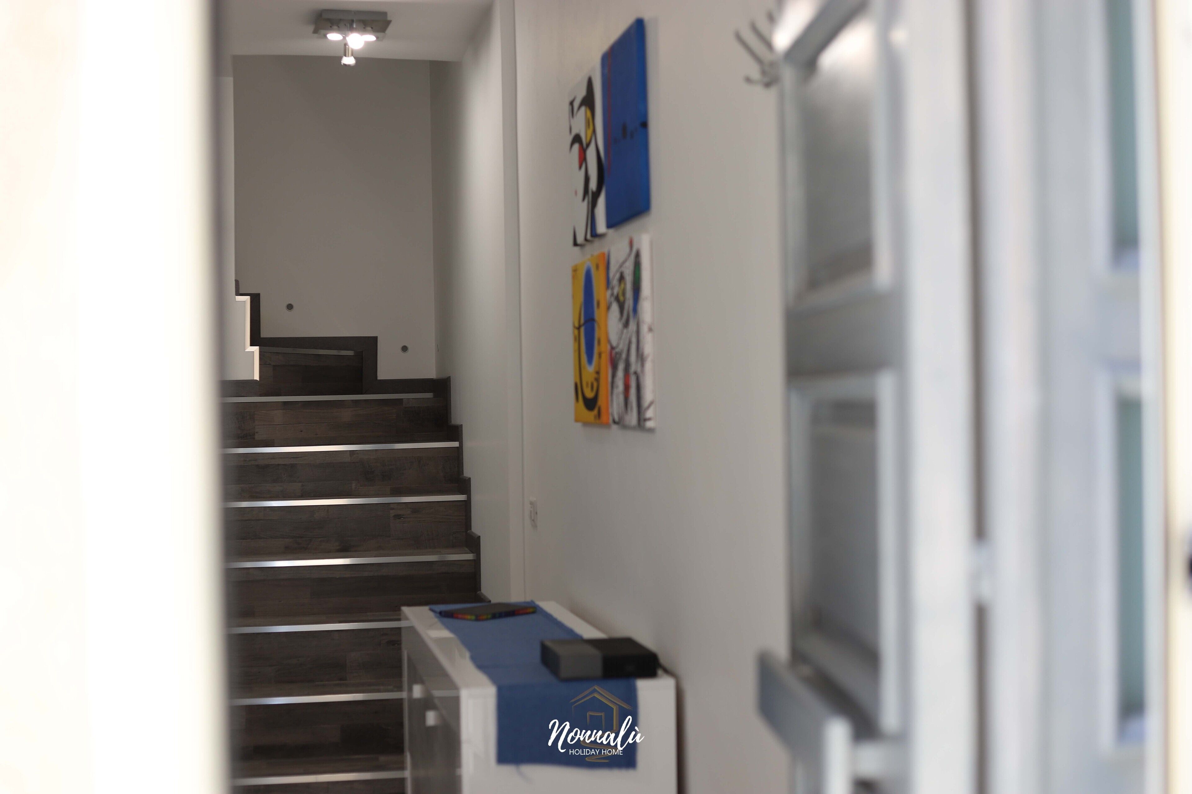 A hotel hallway with a staircase, a reception desk, and artwork on the walls.