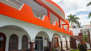 A building with a white and orange facade, multiple balconies, and arched windows. - Cozy Studio/Room Enclosed on an Oceanfront Property at Mima´s Village Cozumel (San Miguel de Cozumel)
