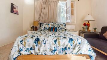 A bedroom with a bed, a bedside table, a lamp, and a view of the outdoors.