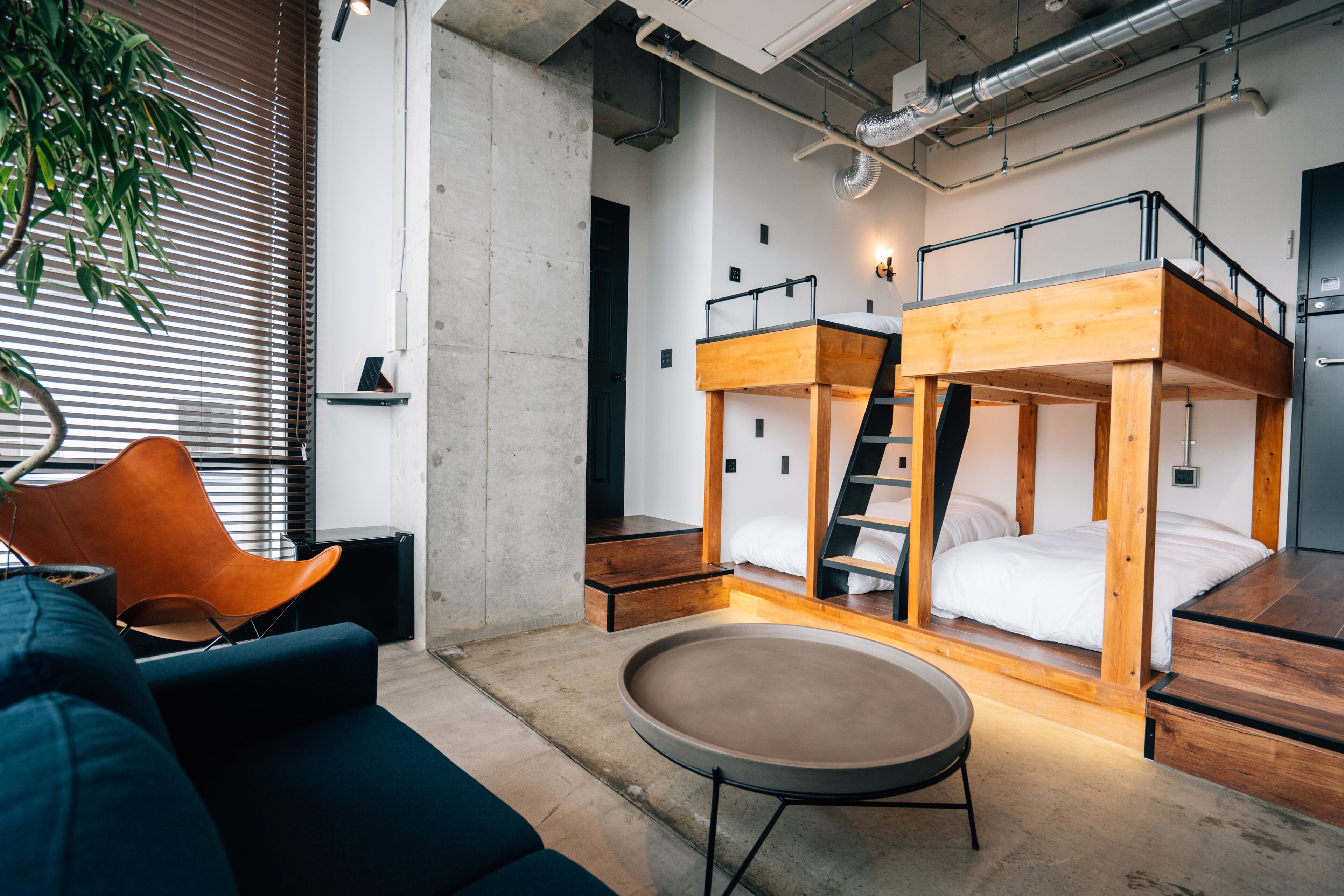A modern, compact room with bunk beds, a round table, and a blue sofa.