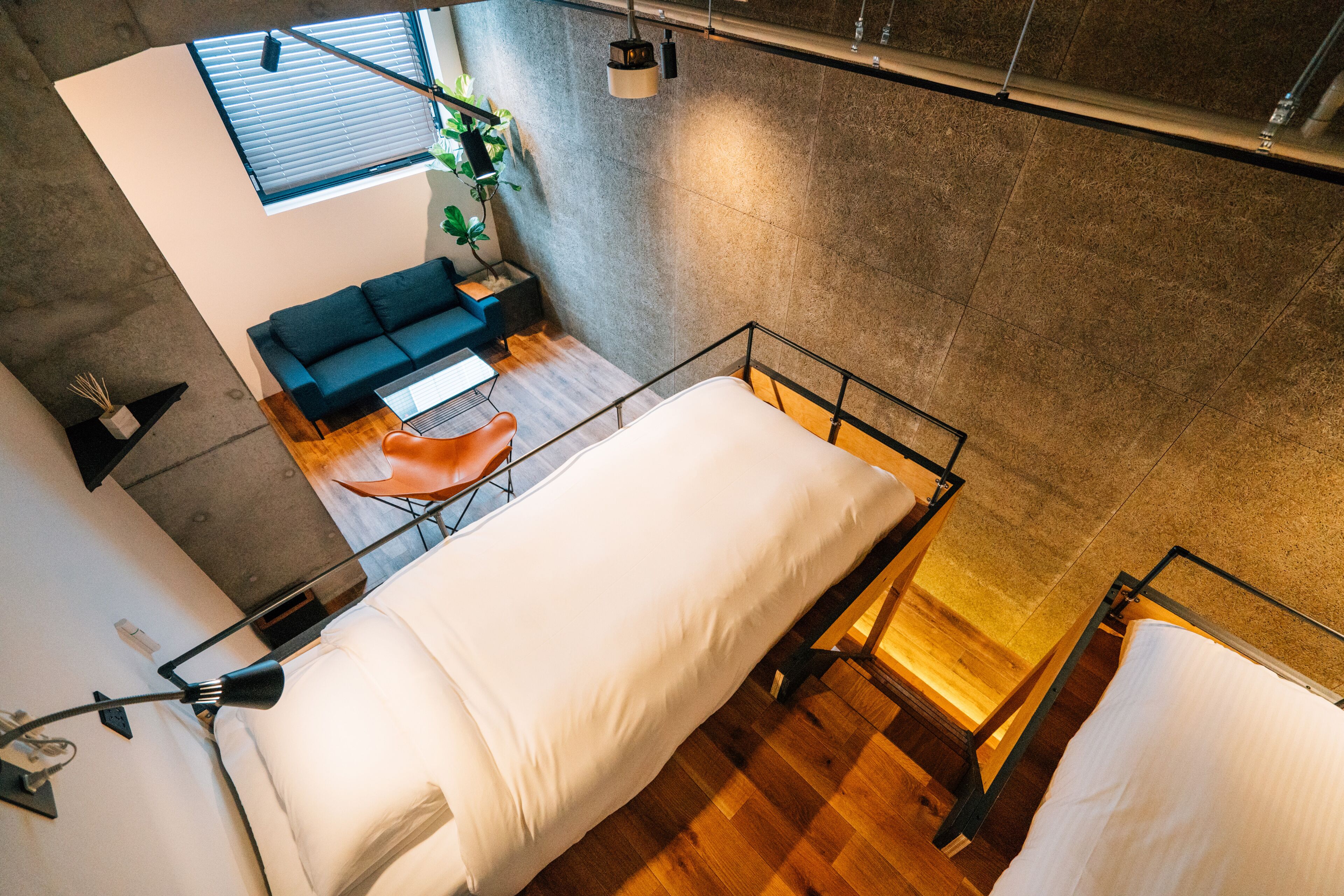 Une chambre moderne de style loft, avec un lit en mezzanine, un petit canapé et un espace bureau.