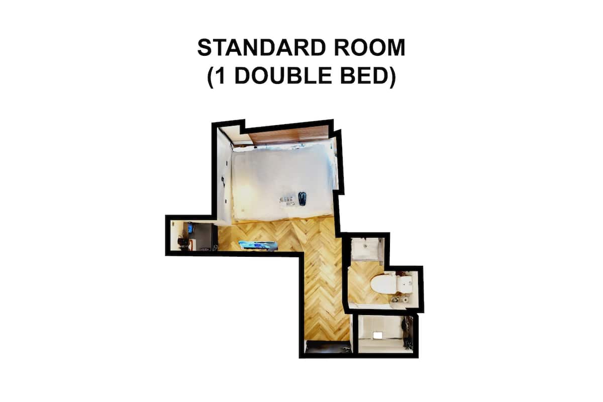 A standard room with one double bed, a wooden floor, a small bathroom, and a visible closet.