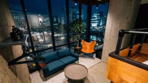 A modern living room with a blue sofa, a round table, and a view of a cityscape at night. - ZONK HOTEL NAKASU-DEAIBASHI (Fukuoka)