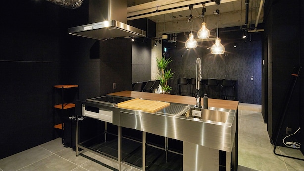 A modern kitchen with stainless steel appliances, a wooden countertop, and hanging pendant lights. - ZONK HOTEL NAKASU-DEAIBASHI (Fukuoka)