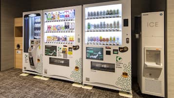 Tres máquinas expendedoras con diversas bebidas y aperitivos, y un dispensador de hielo independiente.