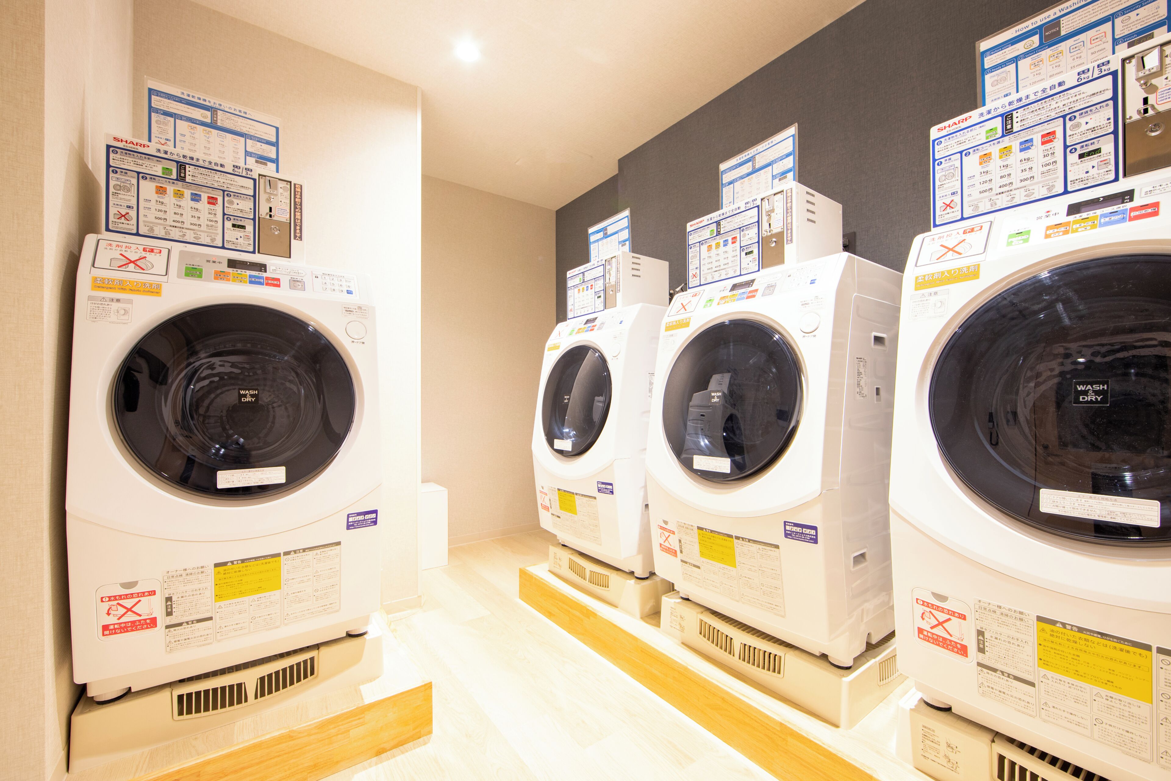 A row of front-loading washing machines in a commercial setting.