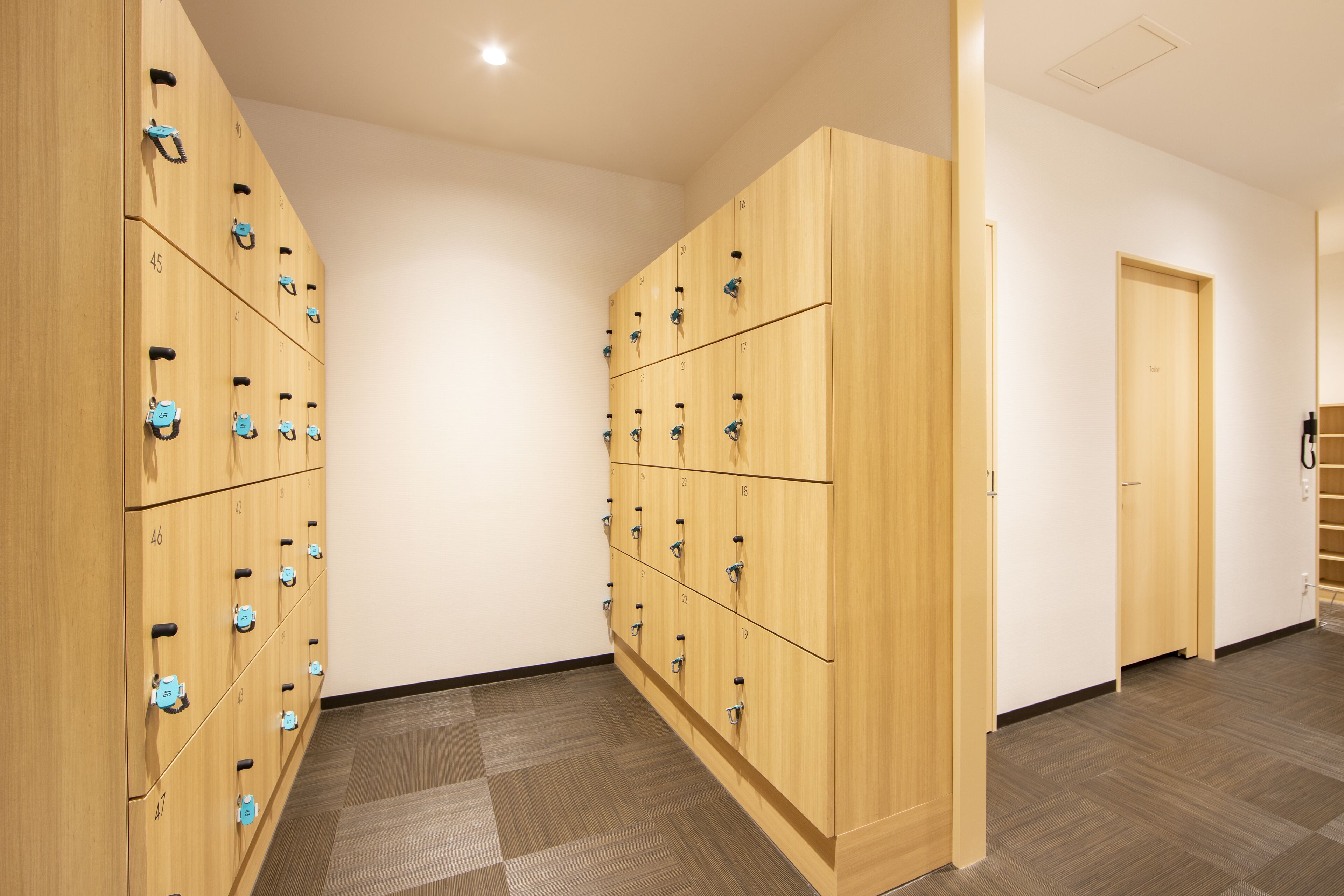 A hotel room with wooden lockers, a wooden door, and a checkered floor.