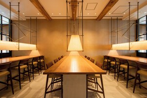 A conference room with a long wooden table, multiple chairs, and pendant lighting.