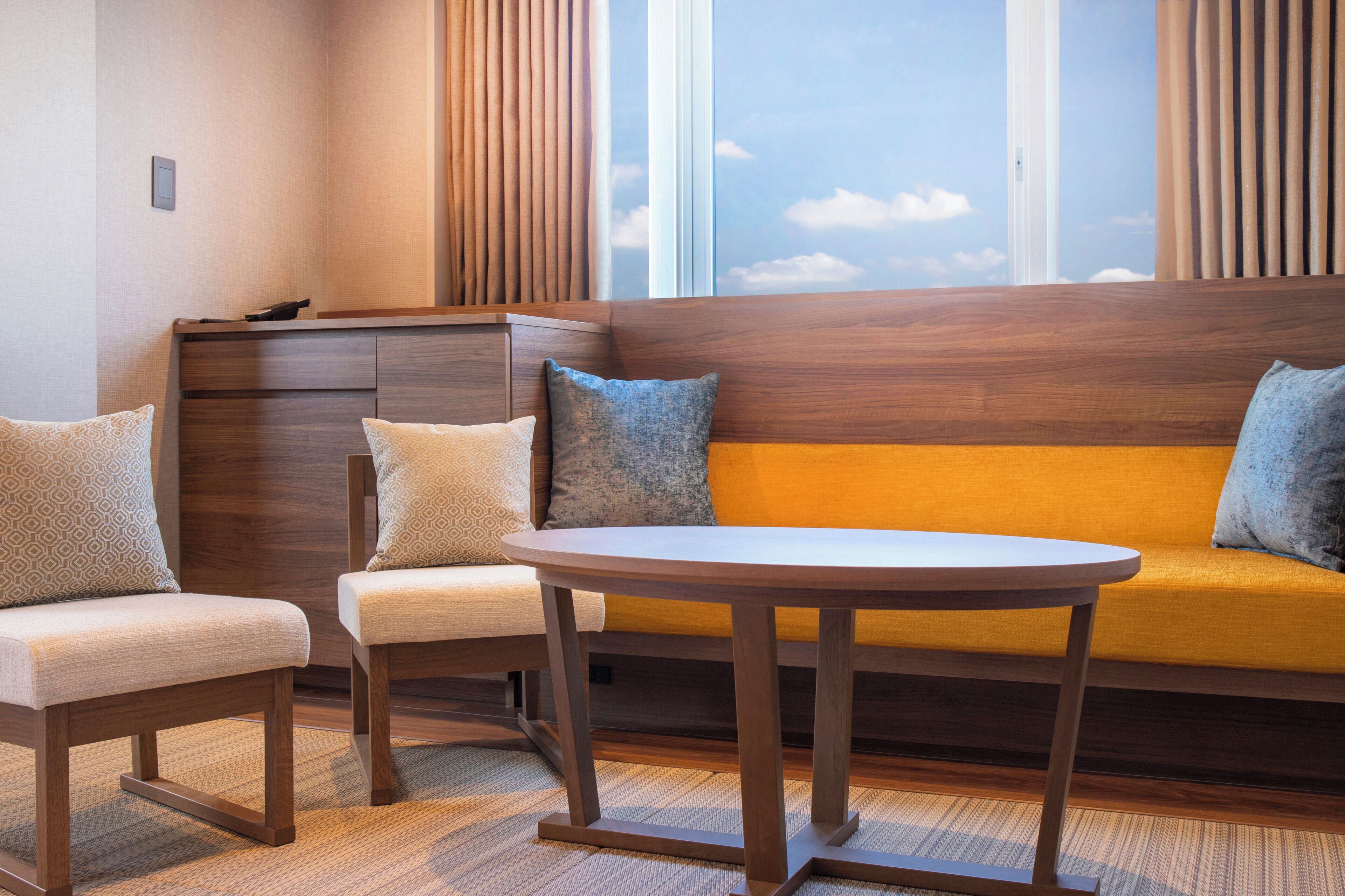 A room with a sofa, two chairs, a small table, and a window with blinds.