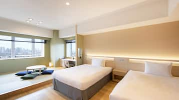 Quarto de hotel moderno com duas camas, uma mesa de trabalho e vista para a cidade.