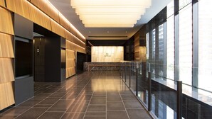 A modern interior with a long corridor, wooden paneling, a marble bench, and large windows.