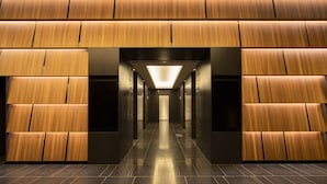 A modern interior with a central corridor flanked by wooden panel walls and a tiled floor.