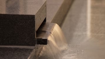Primer plano de una superficie metálica con borde curvo, probablemente parte de un mueble o equipo.