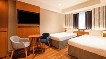 A hotel room with a TV, two beds, a small table, and two chairs.