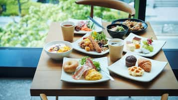Una mesa de desayuno con diversos platos, como huevos, tocino, bollería y un bol de fruta.