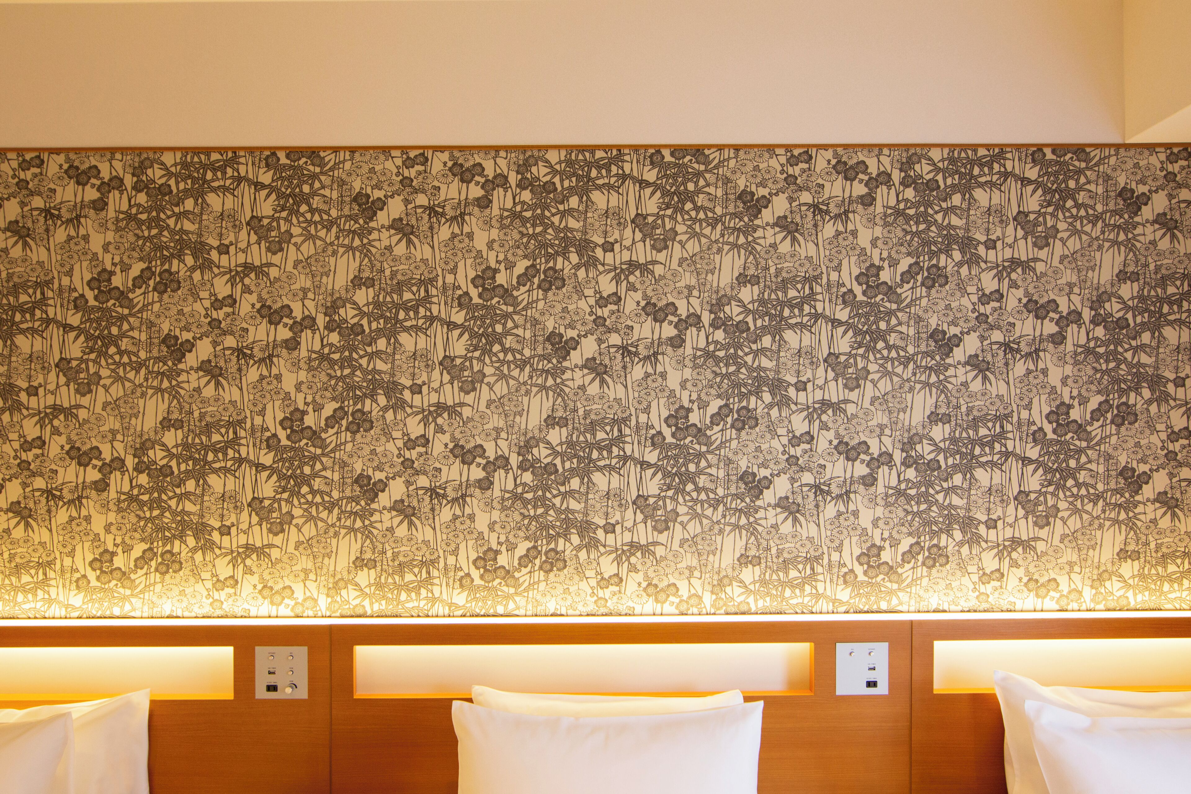 Habitación de hotel con papel tapiz floral, cabecera de madera y almohadas blancas.