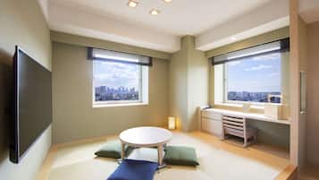 A modern room with tatami flooring, a round table, and a city view through large windows.