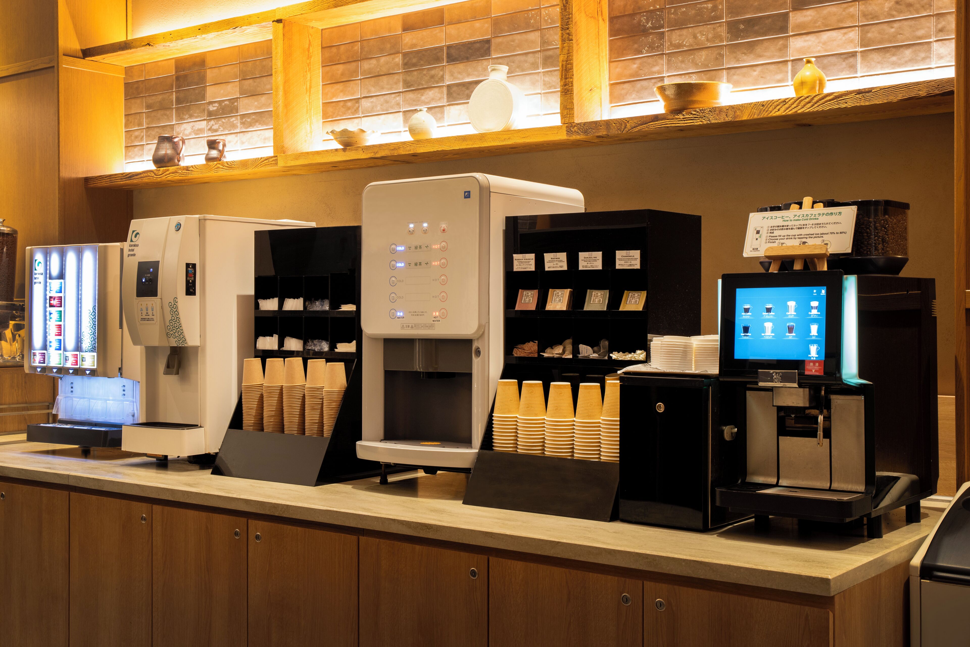 Una cafetería con varias máquinas de café, un dispensador de bebidas y una pantalla de menú.