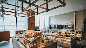A buffet with various food items, a city skyline view through large windows, and a modern interior design.