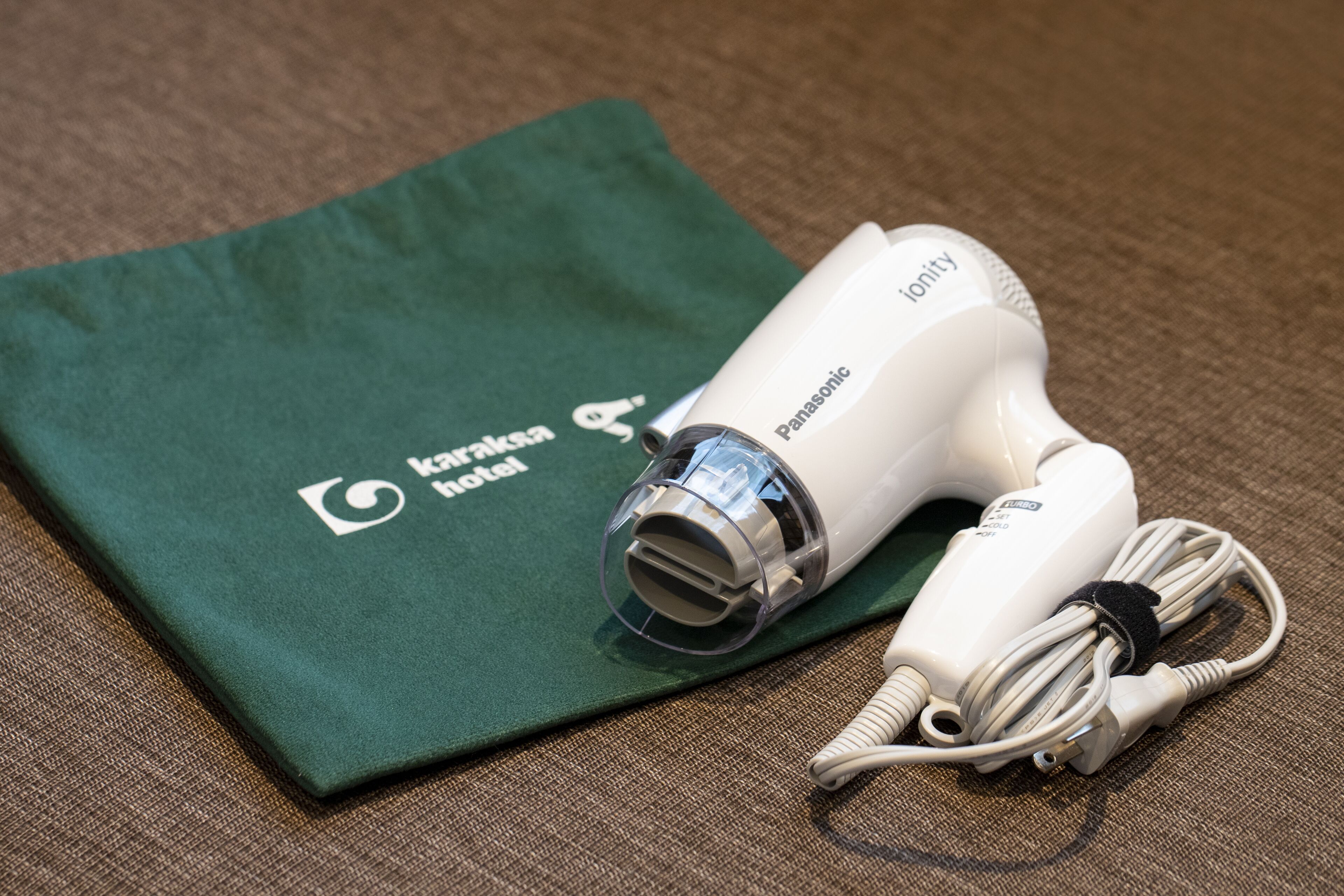 A Panasonic hair dryer and a green cloth with the text "Karimkhan hotel" on it.