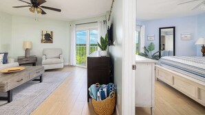 A room with a ceiling fan, a sofa, a coffee table, a TV, a plant, a bed, and a window with a view. - Keys Waterfront Condo: Pool, Beach & Stunning Views! (Tavernier)