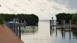 A waterfront walkway with a wooden deck and metal posts. - Keys Waterfront Condo: Pool, Beach & Stunning Views! (Tavernier)
