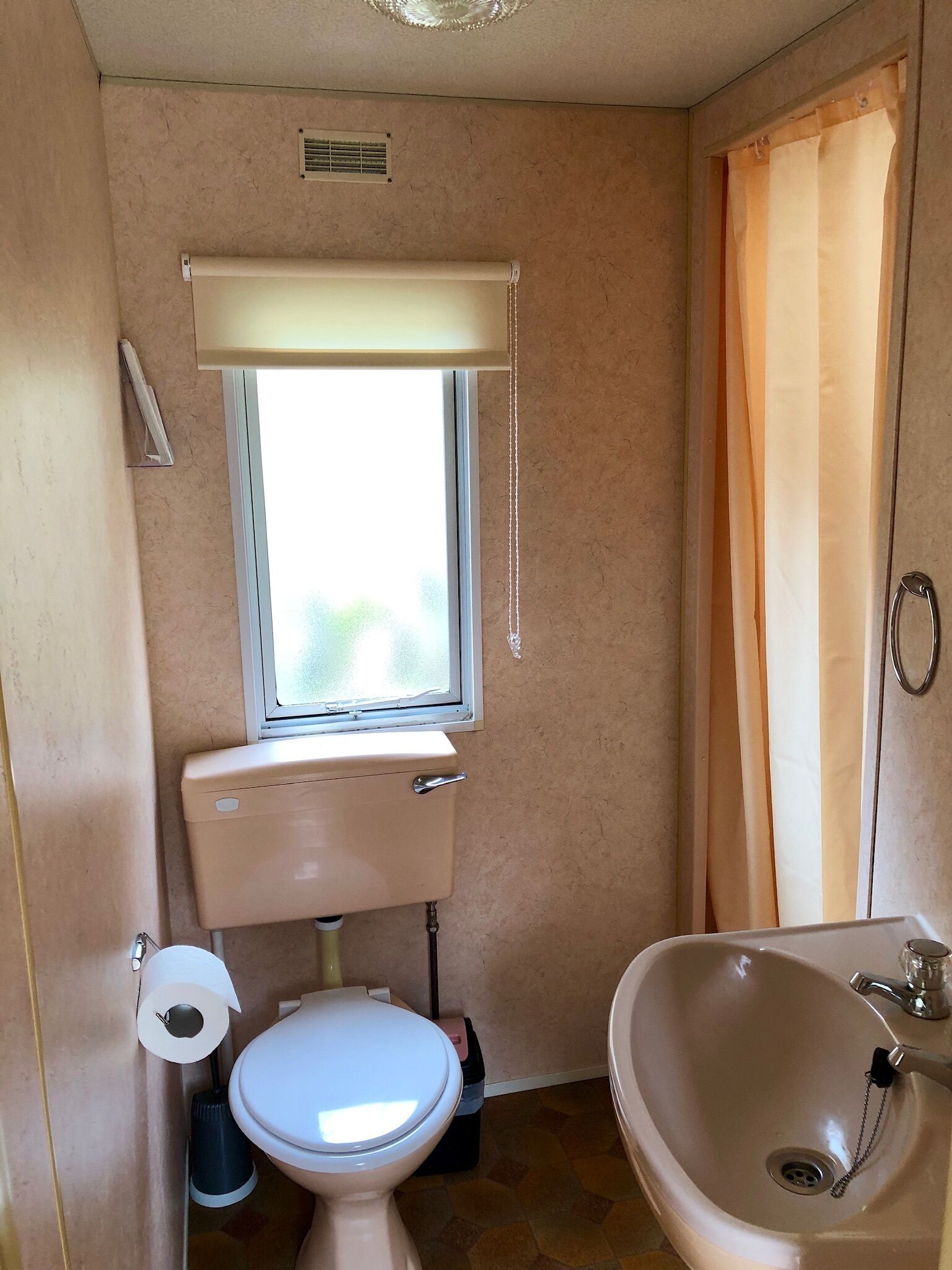 A small bathroom with a toilet, sink, and window.