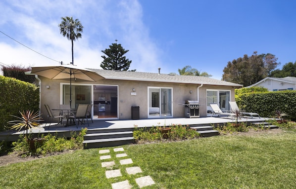 A modern single-story house with a patio, outdoor seating, and a visible garage.