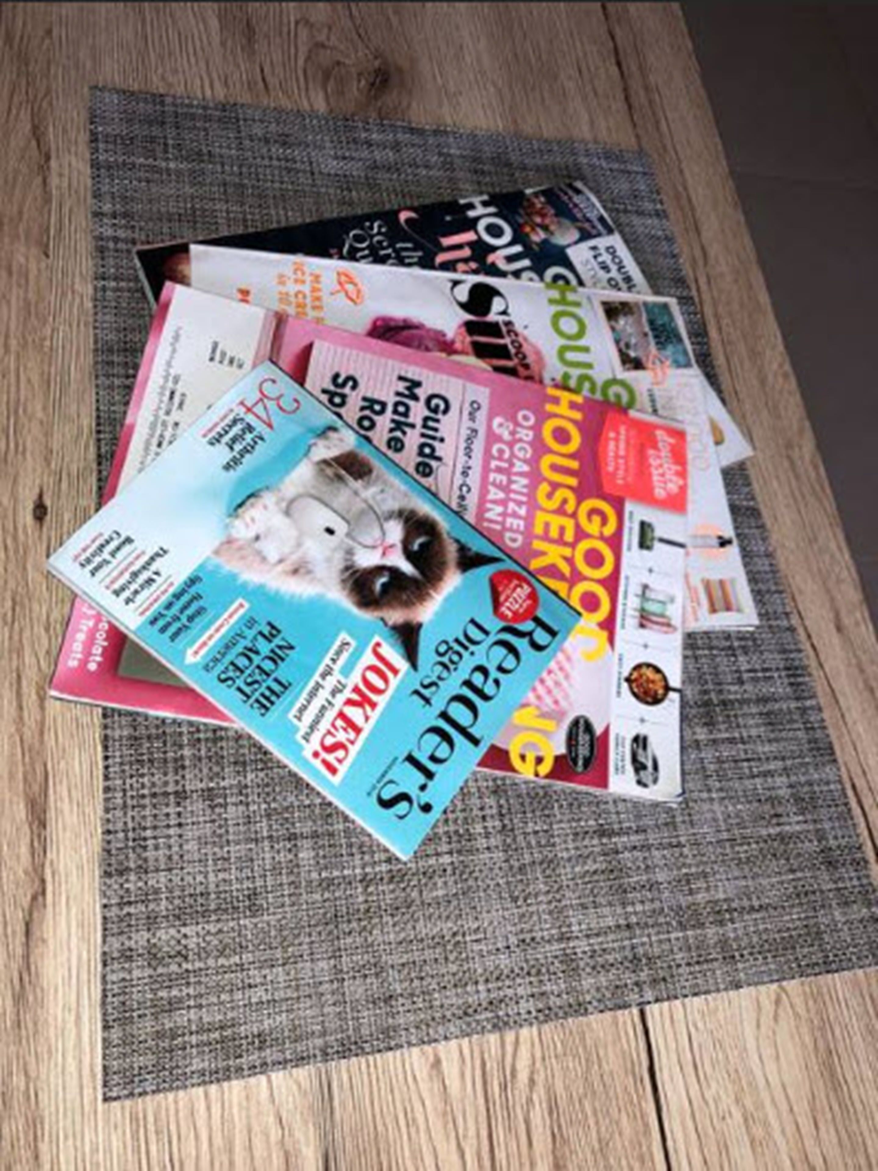 A collection of magazines on a textured grey mat.
