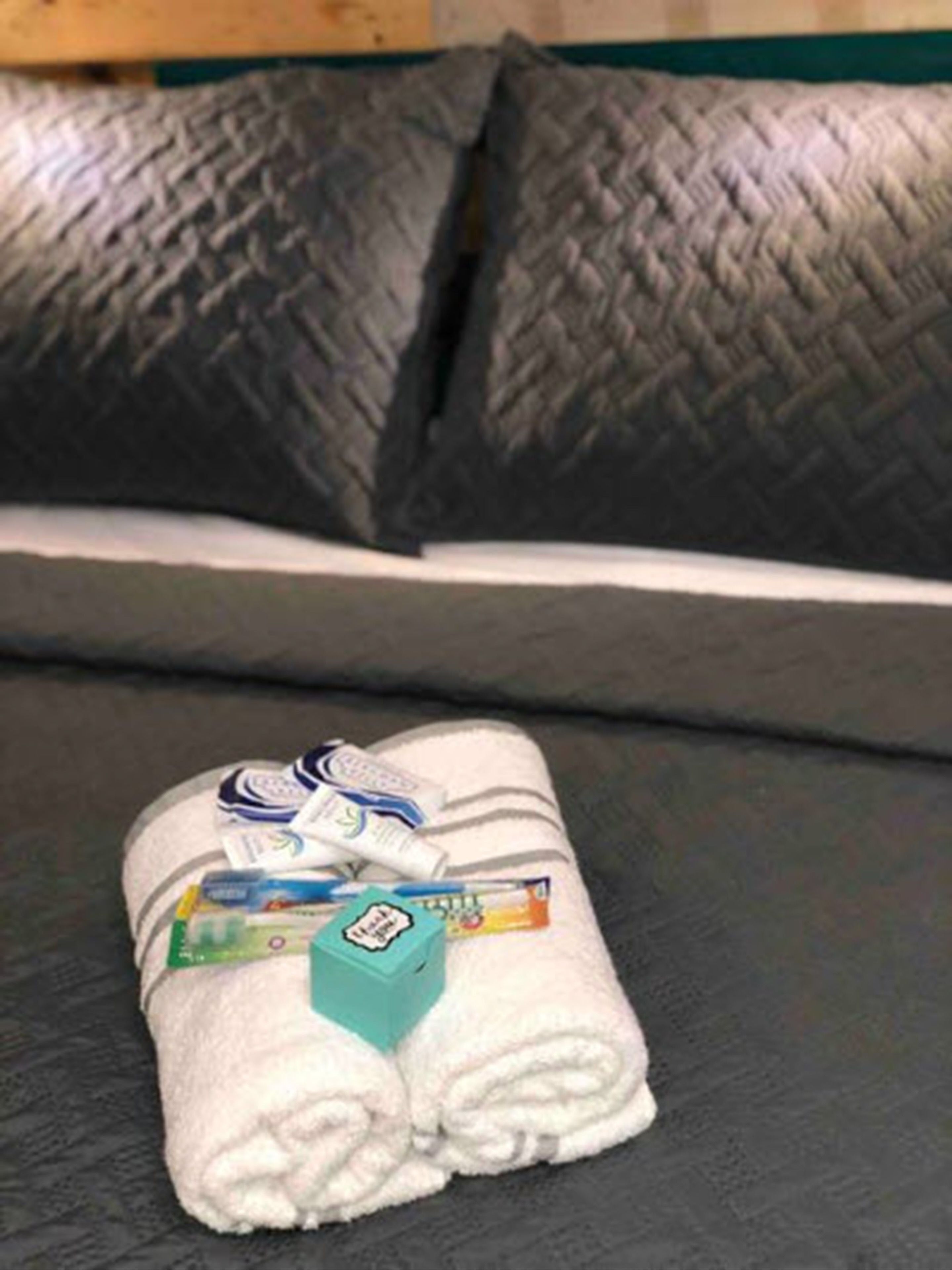 A neatly folded white towel with toiletries on a black sofa.