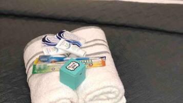 A neatly folded white towel with toiletries on a black sofa.