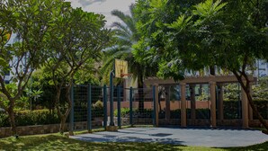 A basketball court surrounded by trees and a fence. - Avida Towers Sucat (Parañaque)