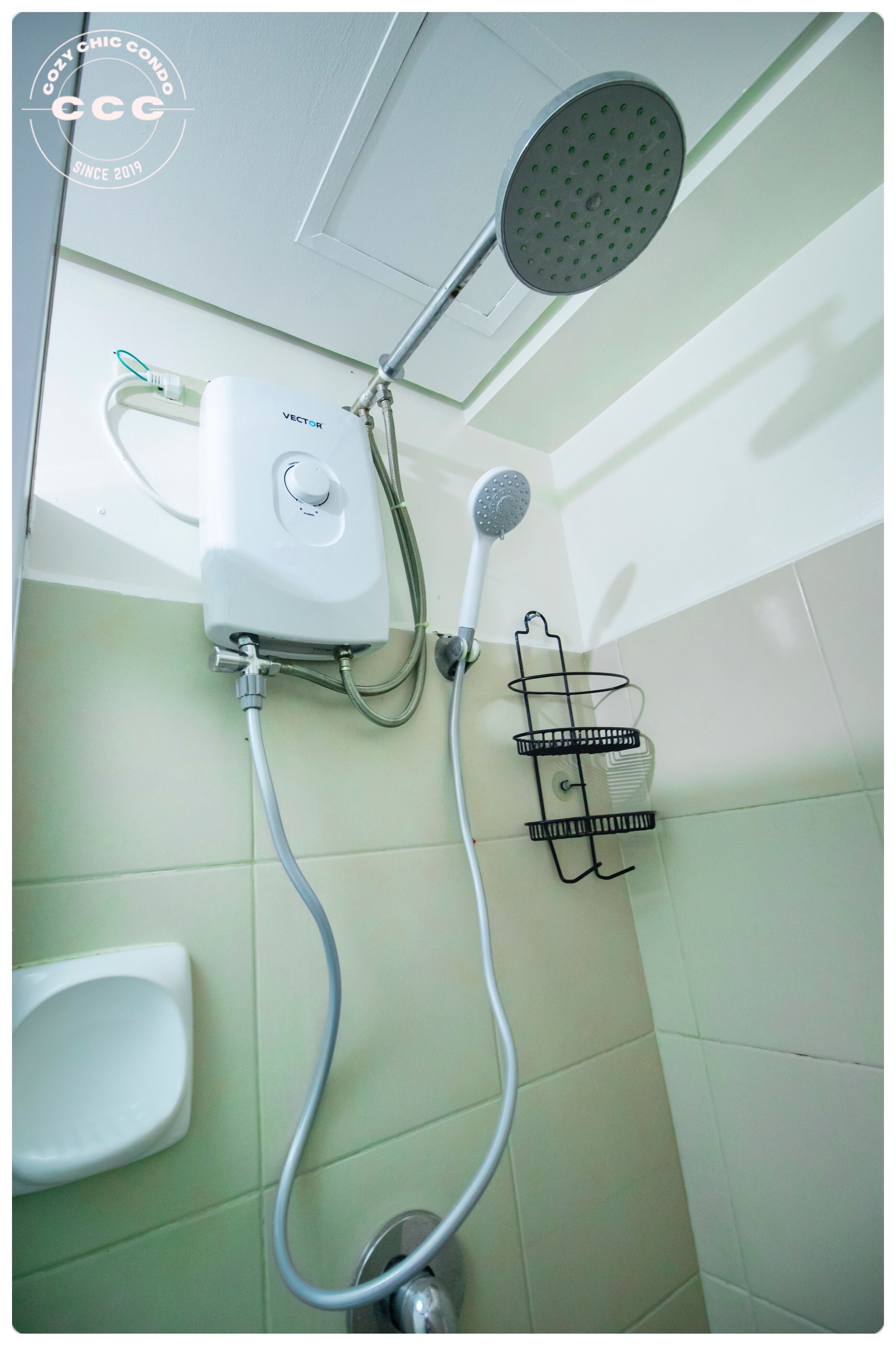 Ducha con cabezal de ducha manual, unidad de control en la pared y un perchero negro.