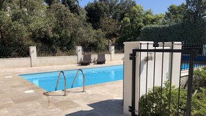 A swimming pool with a metal ladder, surrounded by a tiled patio and a metal gate. - Delightful family friendly villa with new private & heated pool   (Cébazan)