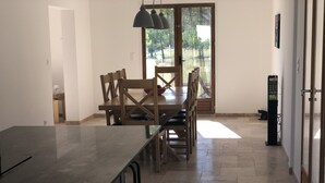 A modern kitchen with a large island, wooden dining table, and chairs. There is a sliding glass door leading to a garden. - Delightful family friendly villa with new private & heated pool   (Cébazan)
