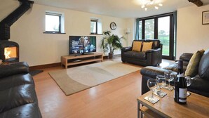 A cozy living room with a fireplace, leather sofas, a TV, and a dining area with wine glasses.